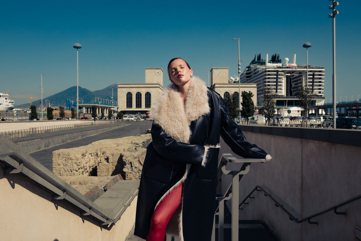 Campagna Éclat d’Automne Spazio22: look con capospalla nero e collo chiaro sul lungomare di Napoli